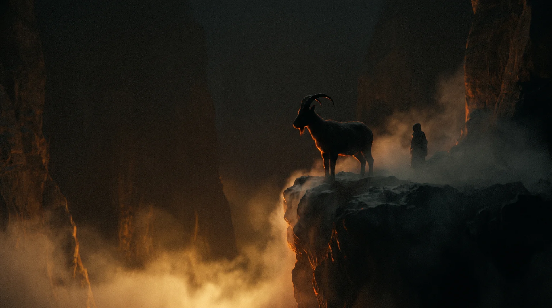 A lone horned goat silhouetted on a cliff edge above a valley of golden morning light